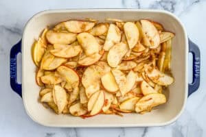 Sliced apples in a baking dish, topped with spices.