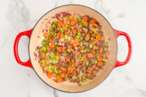 Chopped vegetables and spices cooking together in a pot.