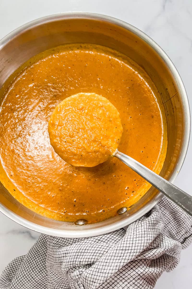 Marry me butternut squash soup being scooped out of a pot with a ladle.