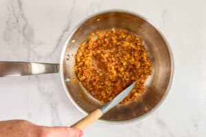 Onions and spices being deglazed in a pot.