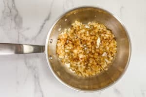 Onions and garlic being cooked in a pot.
