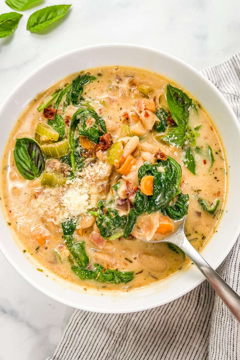 Marry me white bean soup with spinach in a white bowl with a silver spoon.