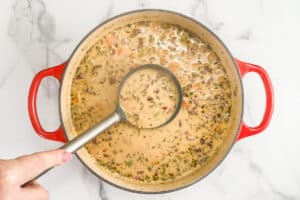 Marry me white bean soup being made in a red pot.