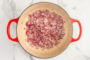 Red onions cooking in a pot.