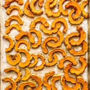 Roasted delicata squash slices on a sheet pan.