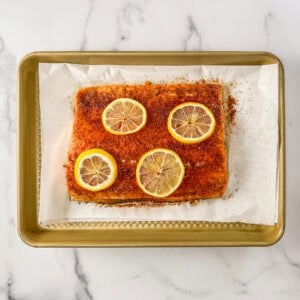 Lemon topped salmon fillet on a sheet pan.