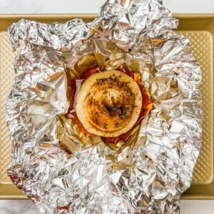 An onion boil on a crumpled piece of aluminum foil on a gold rimmed sheet pan.