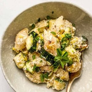 Zucchini and leek baked feta pasta in an offwhite bowl.