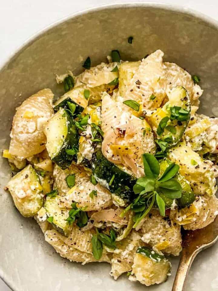 Zucchini and leek baked feta pasta in an offwhite bowl.