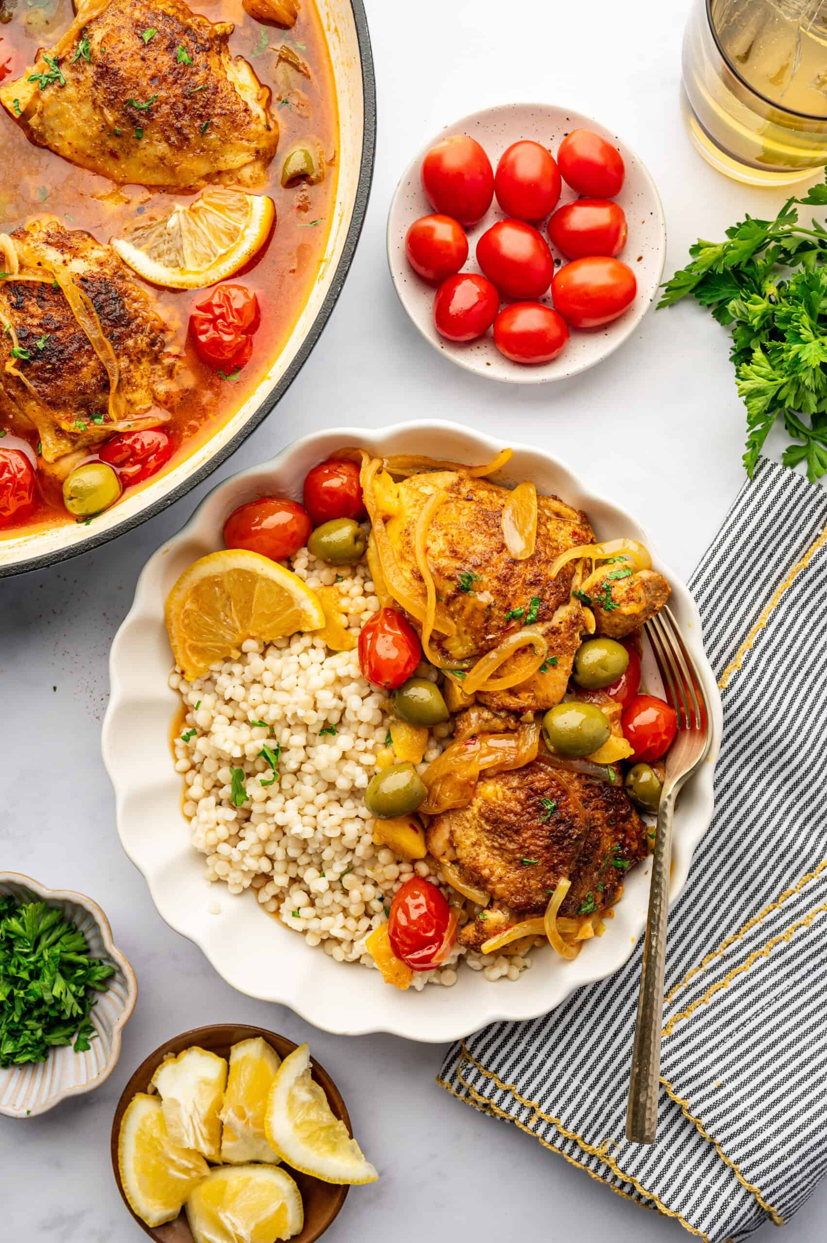 Moroccan chicken with tomatoes, lemon, and green olives in a bowl with couscous.