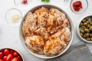 Spiced raw chicken thighs in a bowl.