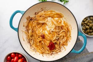 Onions and tomato paste being cooked in a pot.