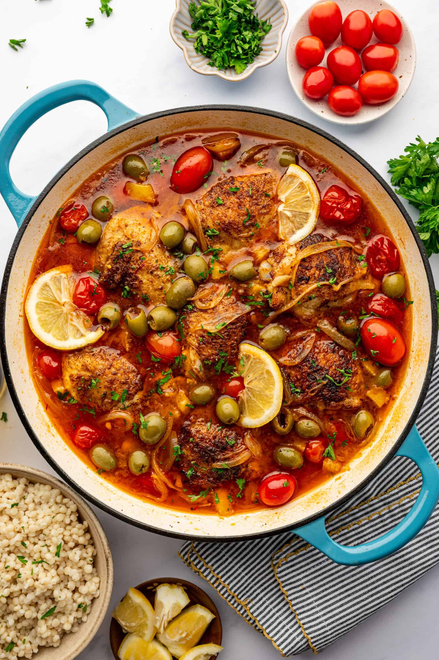 Moroccan chicken with tomatoes and lemon in a teal pot.