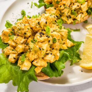 Avocado egg salad on a piece on lettuce on top of a bagel.