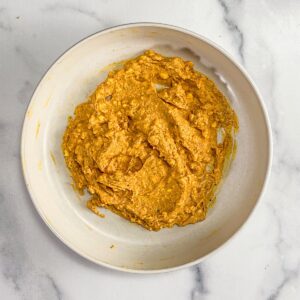 Egg yolks, mayonnaise, and spices mixed in a white bowl.