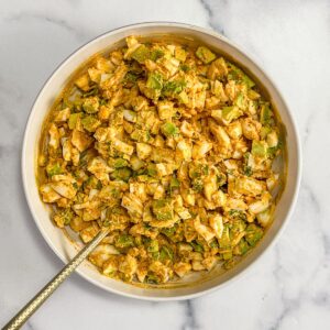 Avocado egg salad being mixed in a white bowl.