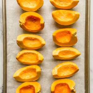 Carnival squash slices on a parchment lined sheet pan.