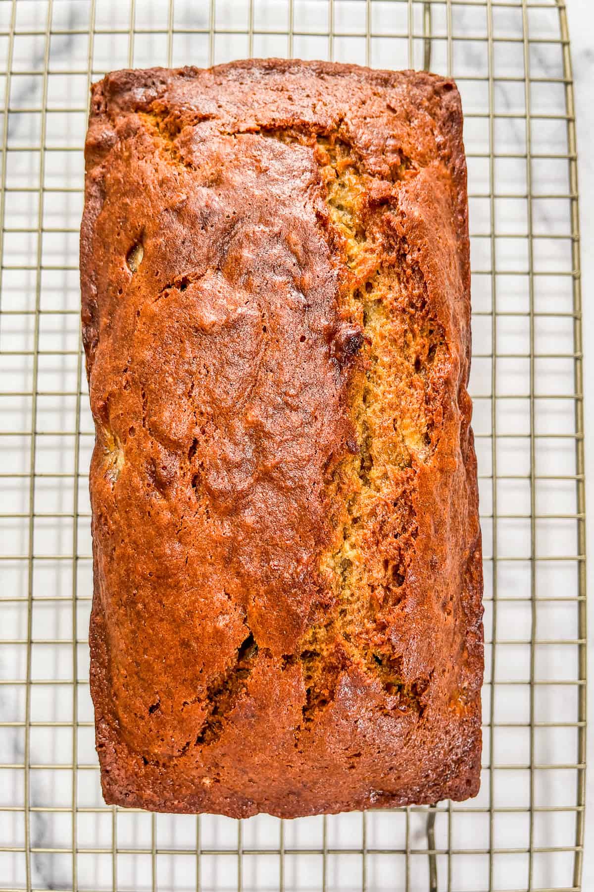 A loaf of cardamom banana bread on a cooling rack.
