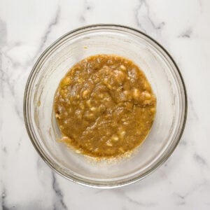 Cardamom banana bread batter being mixed in a large glass bowl.