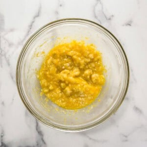 Mashed banana, melted butter, orange juice, and orange zest in a large glass bowl.