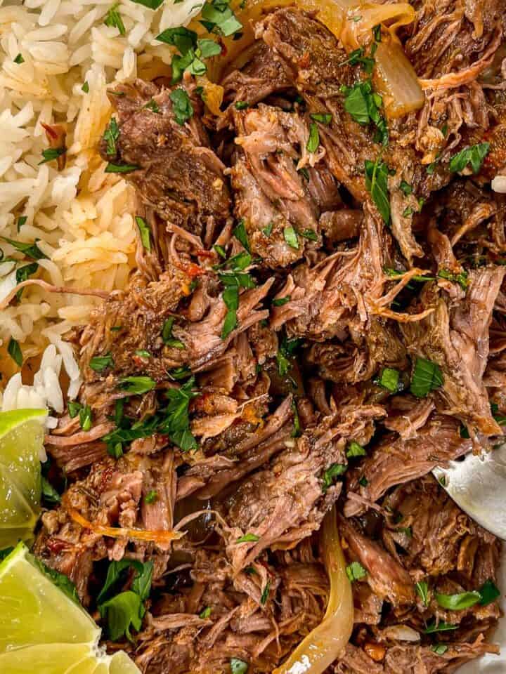 Slow cooker beef barbacoa in a white bowl with rice.