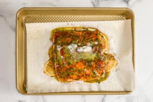 Baked dijon salmon on a piece of parchment on a sheet pan.
