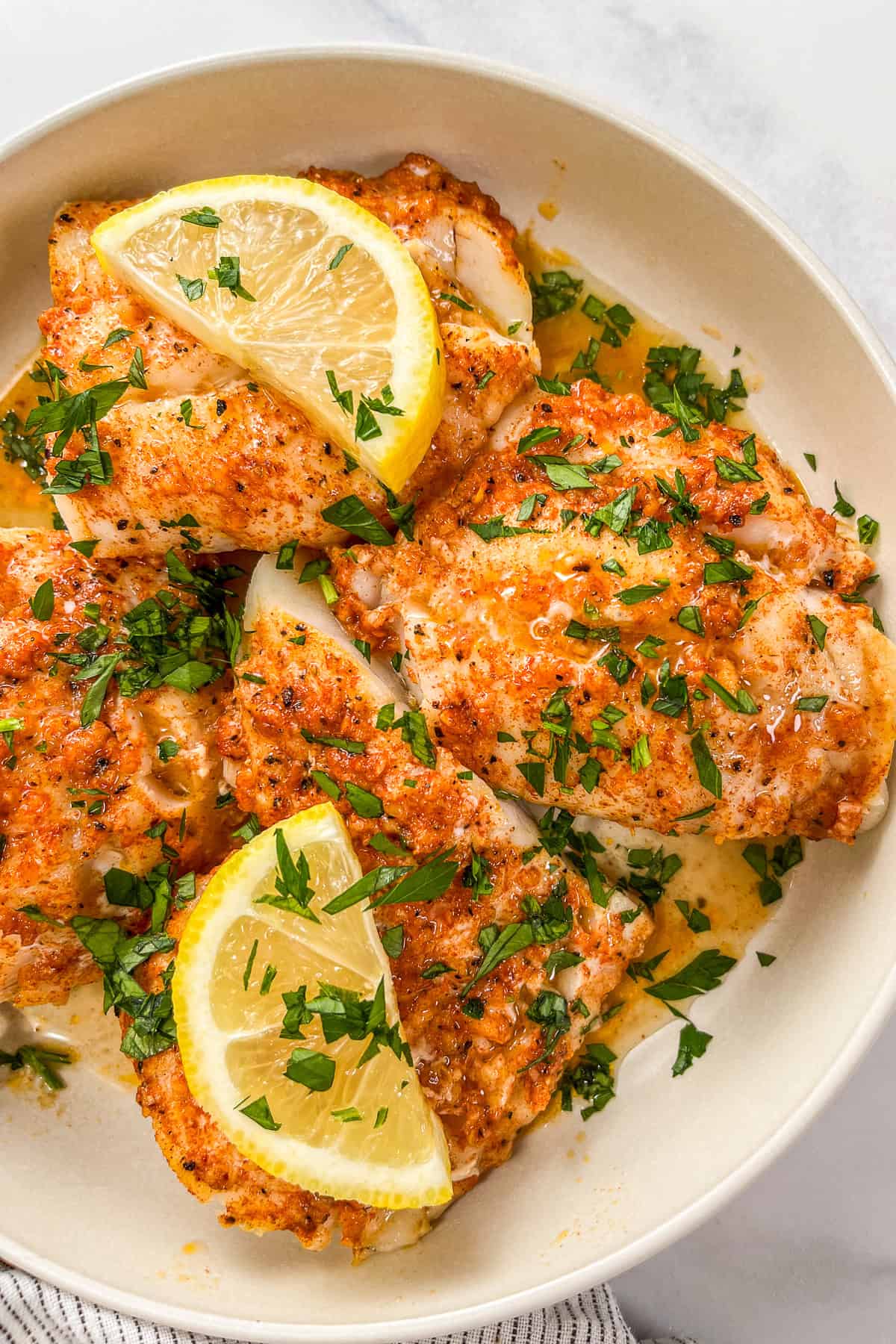 Lemon garlic butter baked cod fillets in a white bowl.