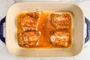 Baked cod in a lemon garlic butter sauce in a baking dish.