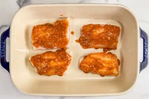 Cod fillets topped with a spiced lemon garlic butter sauce in a baking dish.