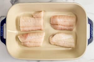 Four cod fillets in a baking dish.