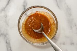 Lemon garlic butter sauce with spices in a glass bowl with a silver spoon.