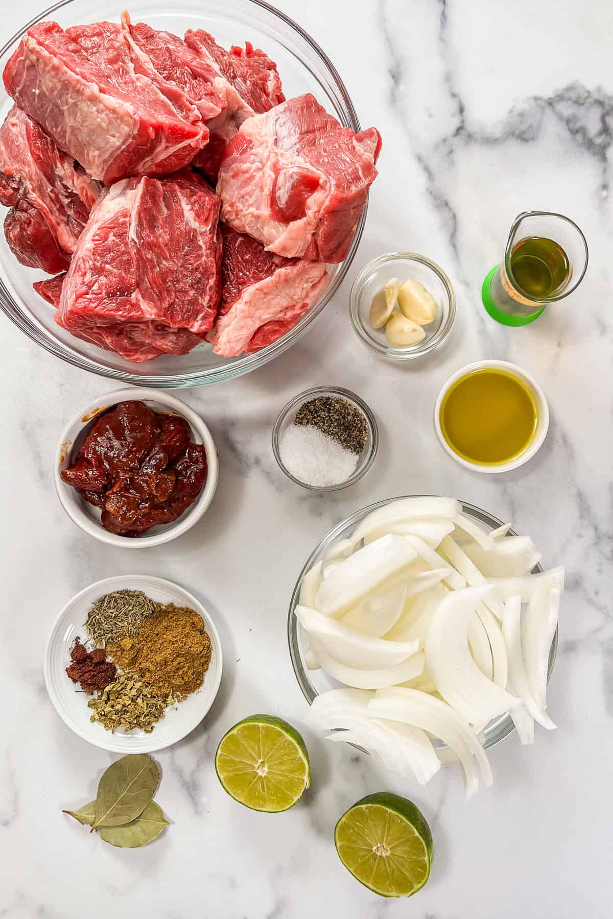 Ingredients for slow cooker beef barbacoa on a marble background.