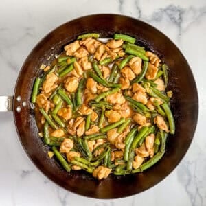 Chicken and green bean stir fry in a large pan.