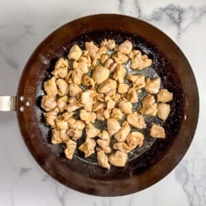 Chicken chunks cooking a large pan.