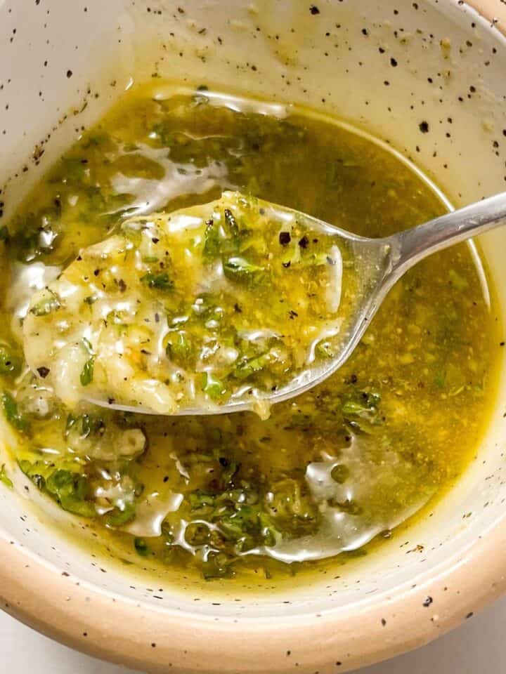 Greek marinade in a speckled bowl with a silver spoon.