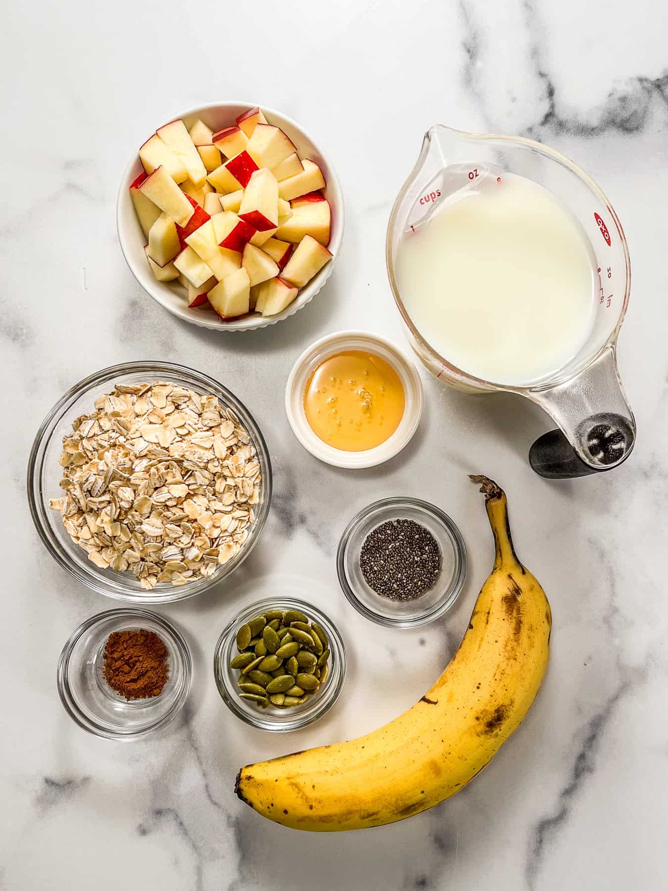 Ingredients for pumpkin spice oatmeal on a marble background.