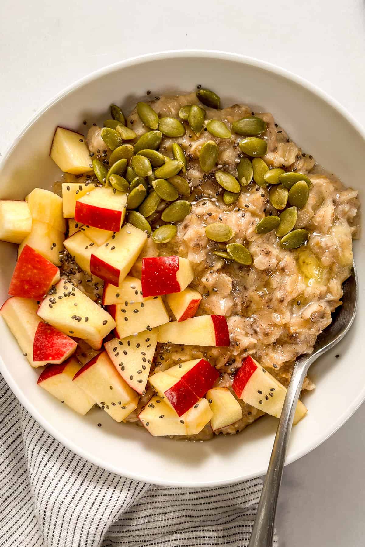 Pumpkin spice oatmeal topped with pepitas and chopped apples.
