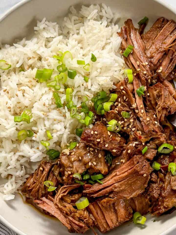Slow cooker beef bulgogi with rice in a white bowl.