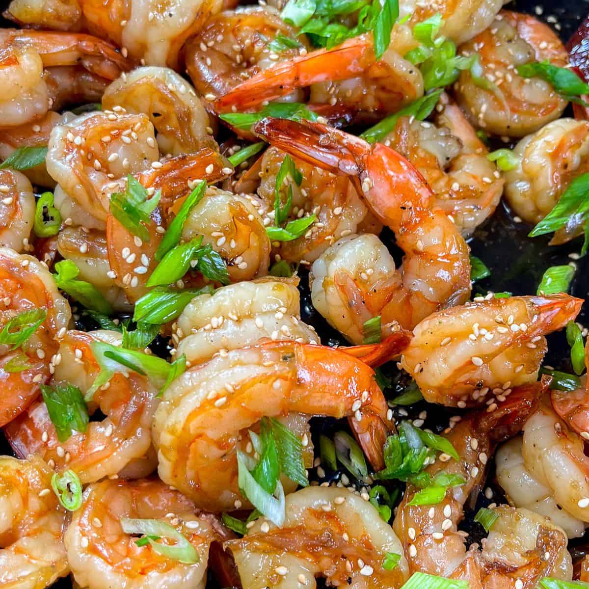 Honey soy garlic shrimp topped with sliced green onions and sesame seeds.