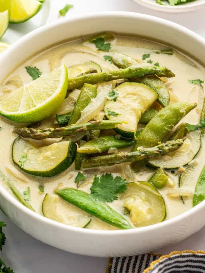 Thai green curry with a lime wedge in a white bowl.
