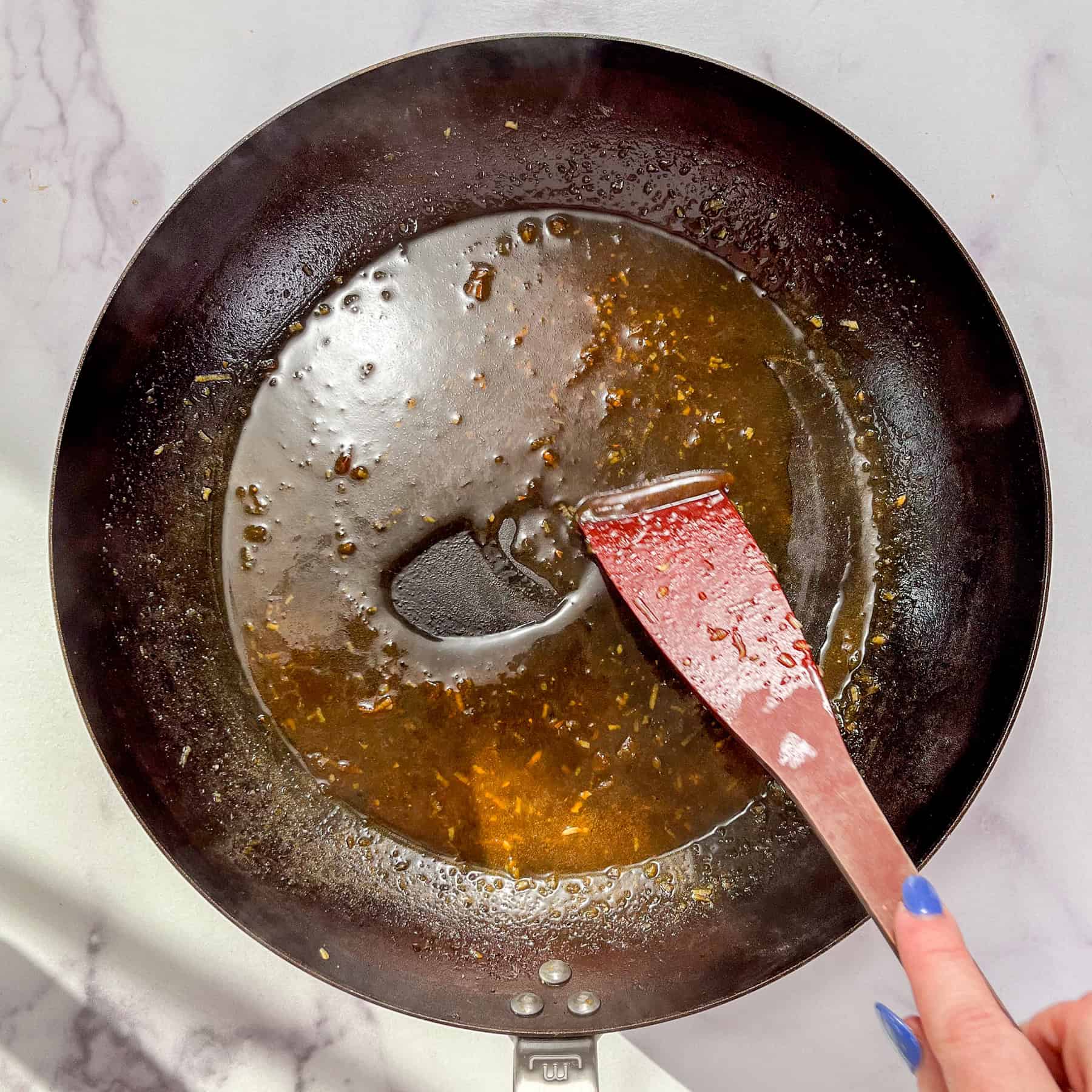 Soy honey garlic sauce being reduced in a frying pan.