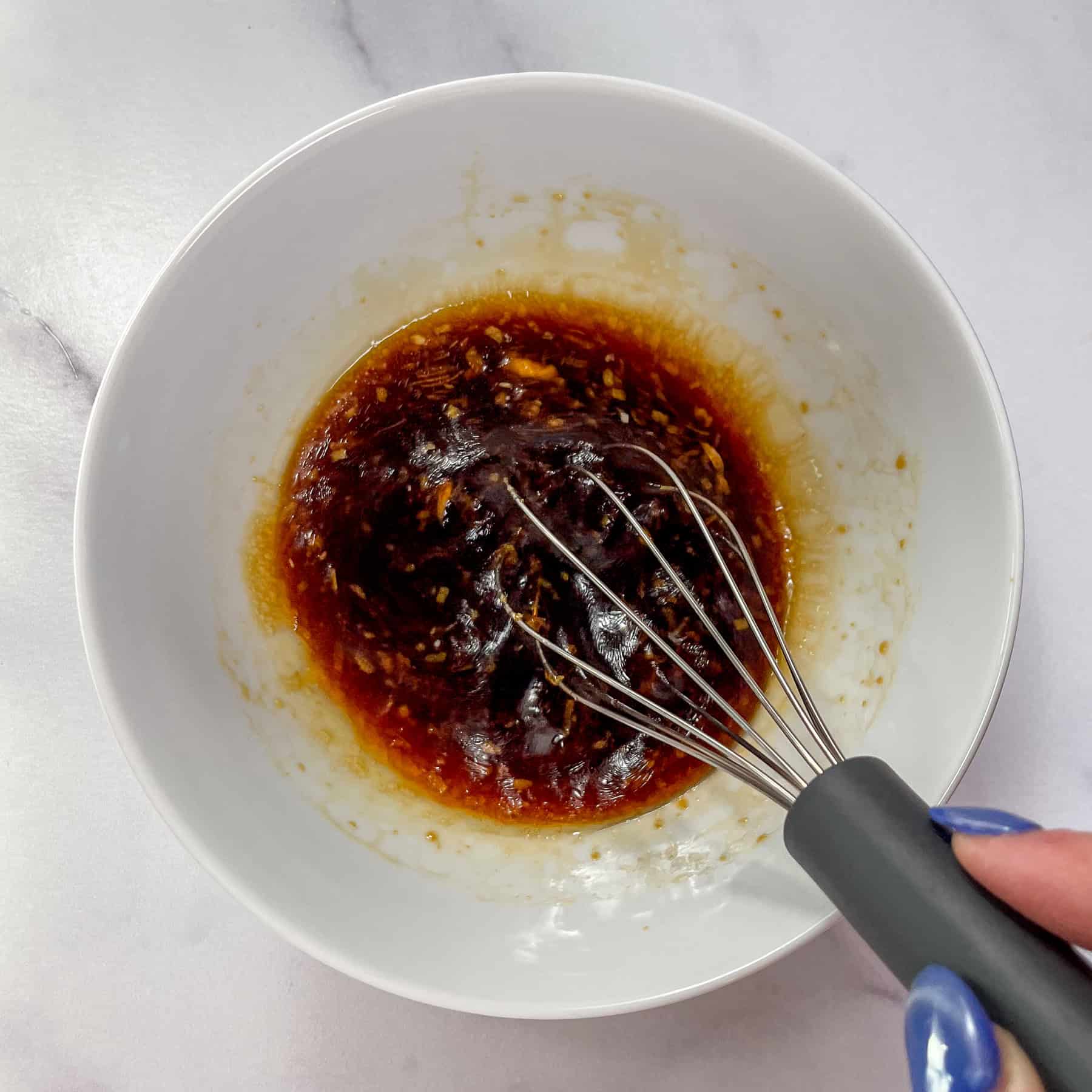 Soy garlic honey sauce being whisked in a white bowl.