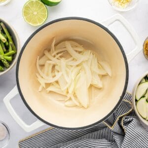 Cooking onions in a white dutch oven.