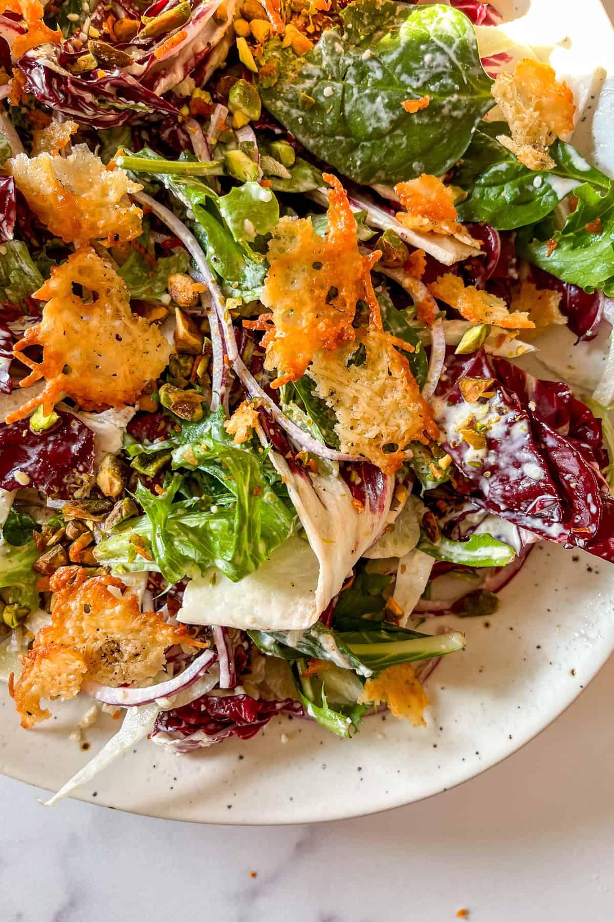 Winter salad with Caesar dressing, greens, and onions on a large platter.