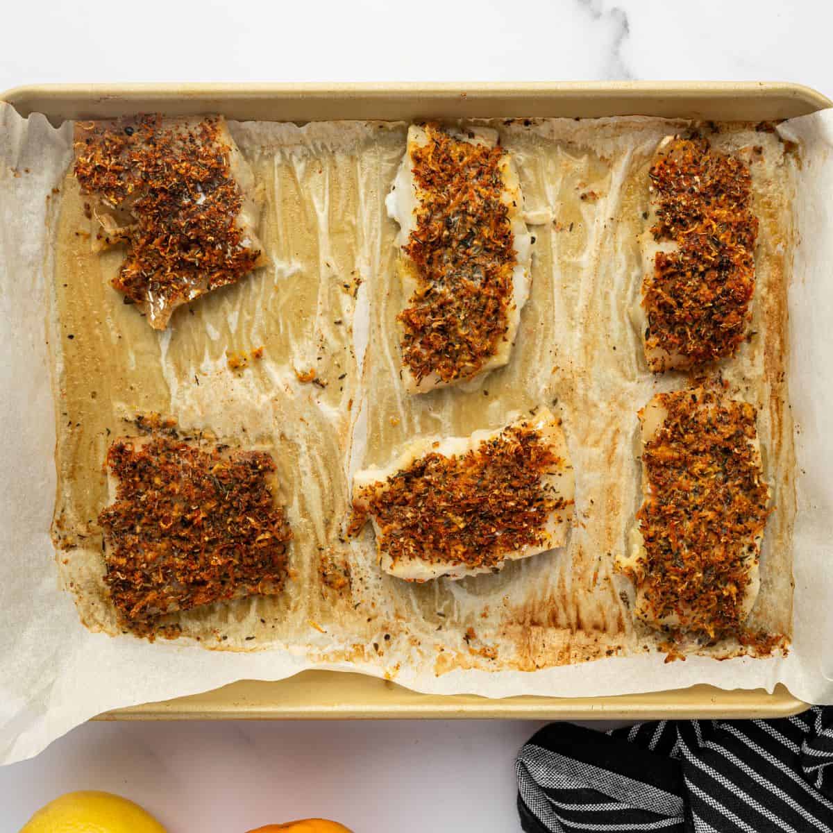 Baked citrus cod on a parchment lined sheet pan.