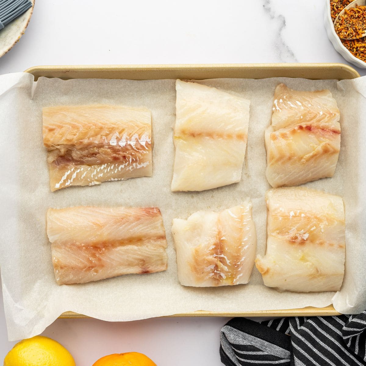 Piece of cod on a parchment lined baking sheet.