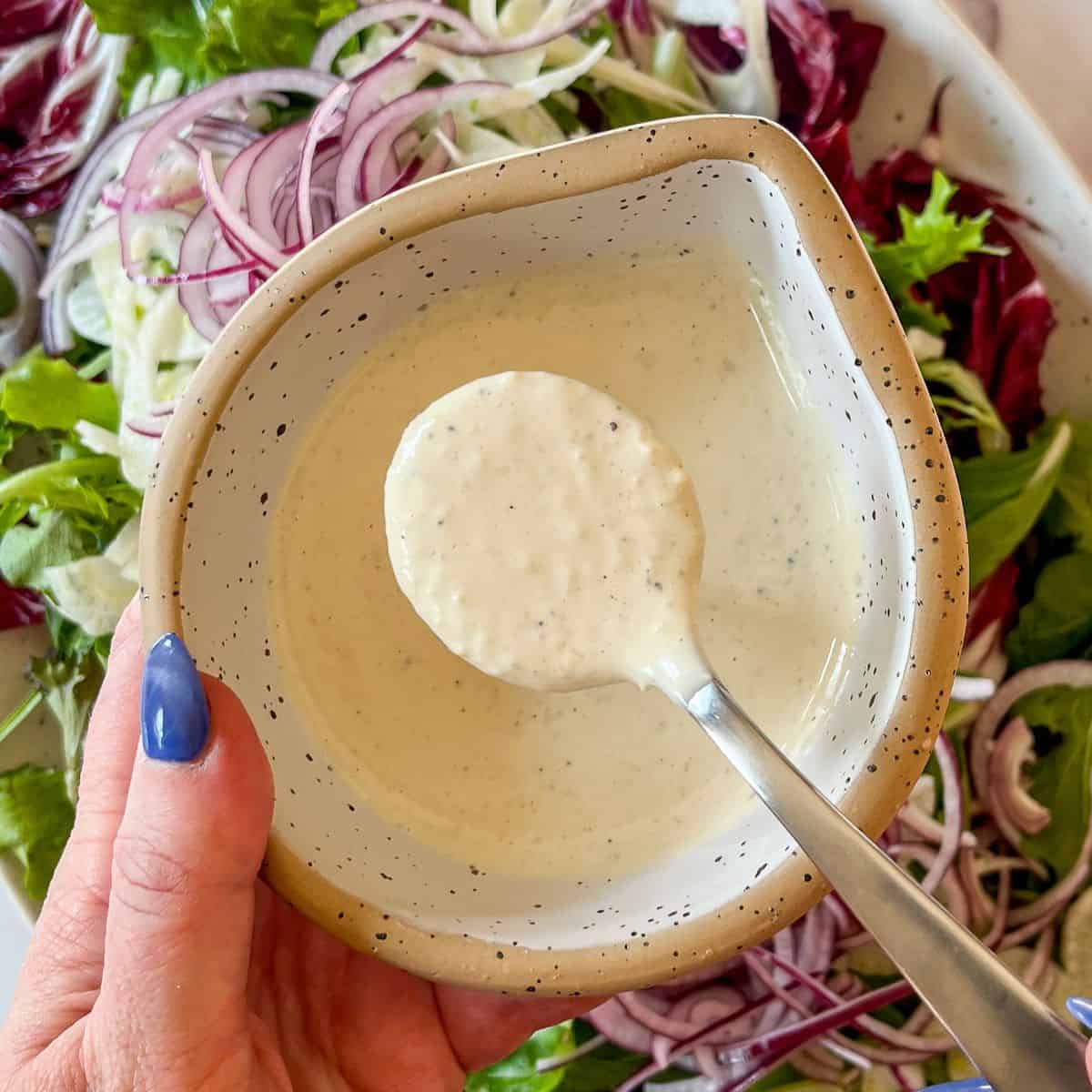 Homemade caesar dressing in a bowl over a salad.