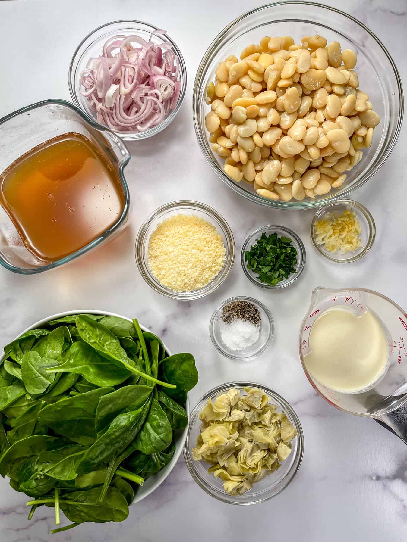Ingredients for spinach artichoke butter beans in bowls.