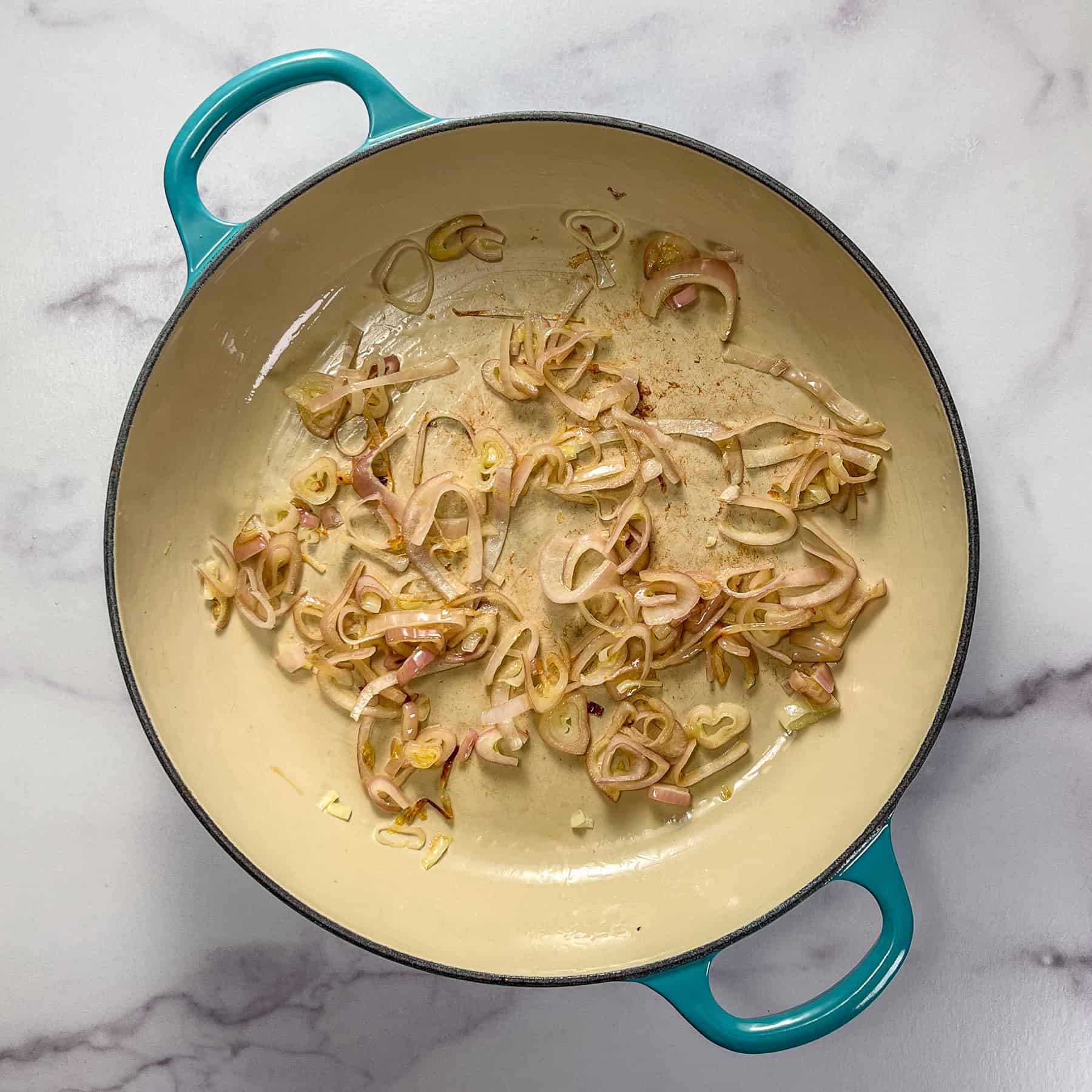Shallots cooking in a braiser pan.