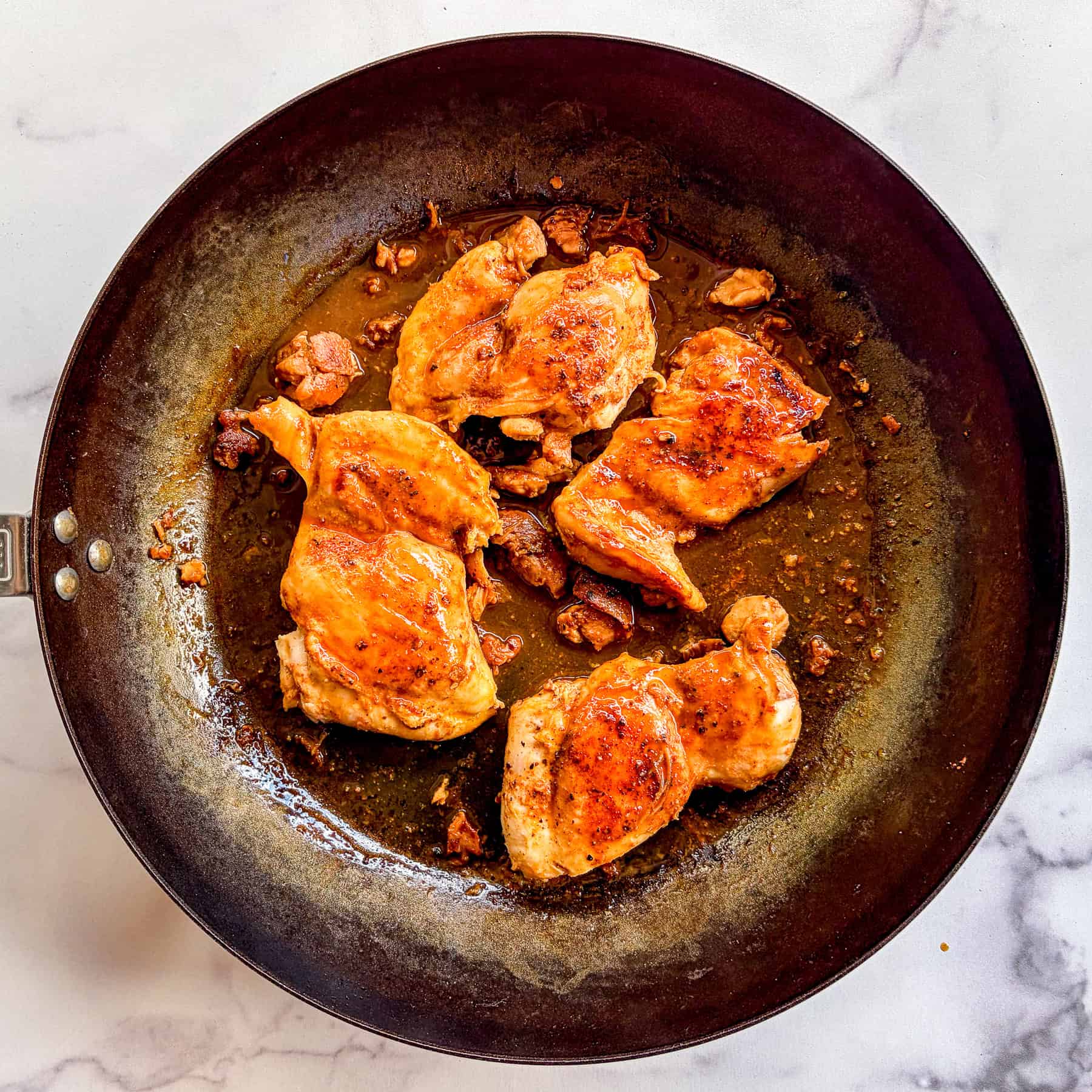 Sauteed chicken thighs in a skillet.